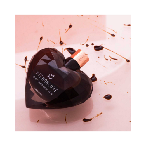 طلاء الجسم High on Love Dark Chocolate على خلفية وردية مع قطرات من الشوكولاتة، يُظهر استخدامه اللطيف والمرح للعناية بالجسم.