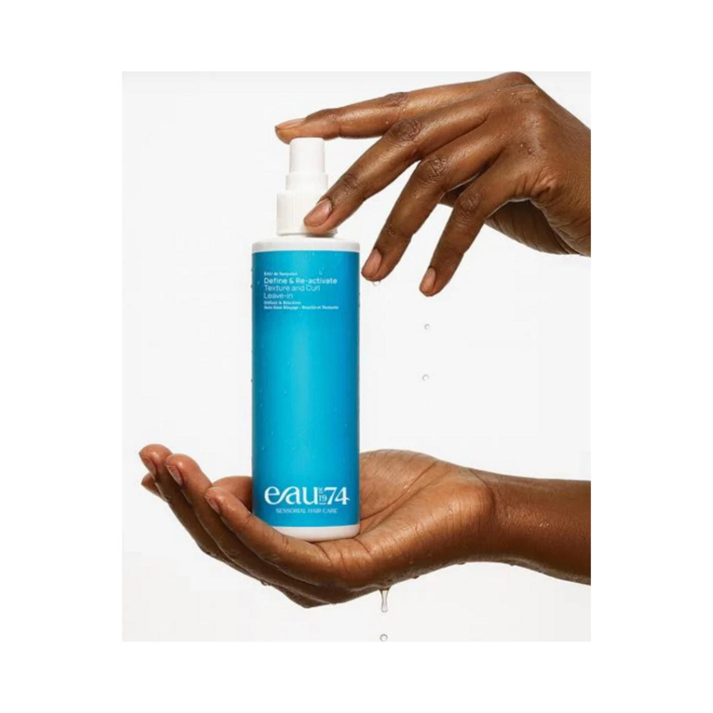 Hände halten EAUde1974 Leave-In Hair Spray mit Wassertropfen