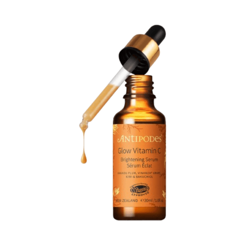 Antipodes Glow Ritual C-vitamiiniseerumi meripihkanruskeassa lasipullossa kultaisella tiputtimella, suunniteltu kirkastamaan ja ikääntymistä ehkäisevään ihonhoitoon.