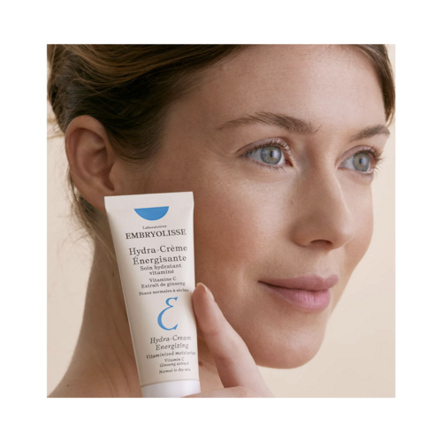 Bean le craiceann radiantach a bhfuil Embryolisse Hydra Cream Energizing, uachtar aghaidh moisturizing le Vitimín C agus ginseng le haghaidh cúram craicinn tirim.