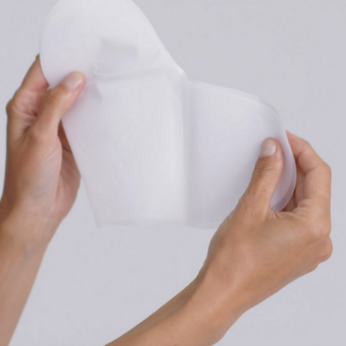 Omnilux Hydrogel Decollete Mask טיפול גוף נפתח ביד, מראה את מרקם ההידרוג'ל תואם LED שלה לשימוש בטיפוח העור.