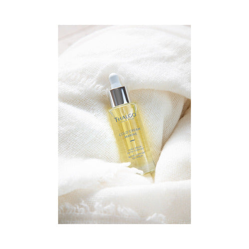 Thalgo Cold Cream Marine Nutri-Comfort Oil-Serum-flaske plassert i mykt stoff, som symboliserer komfort og hudnæring.