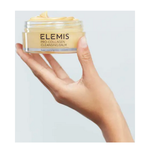 يحمل برطمان Elemis Pro-Collagen Cleansing Balm باليد ويعرض ملمس المنتج وتغليف المستخدم لتنظيف الوجه والعناية بالبشرة.