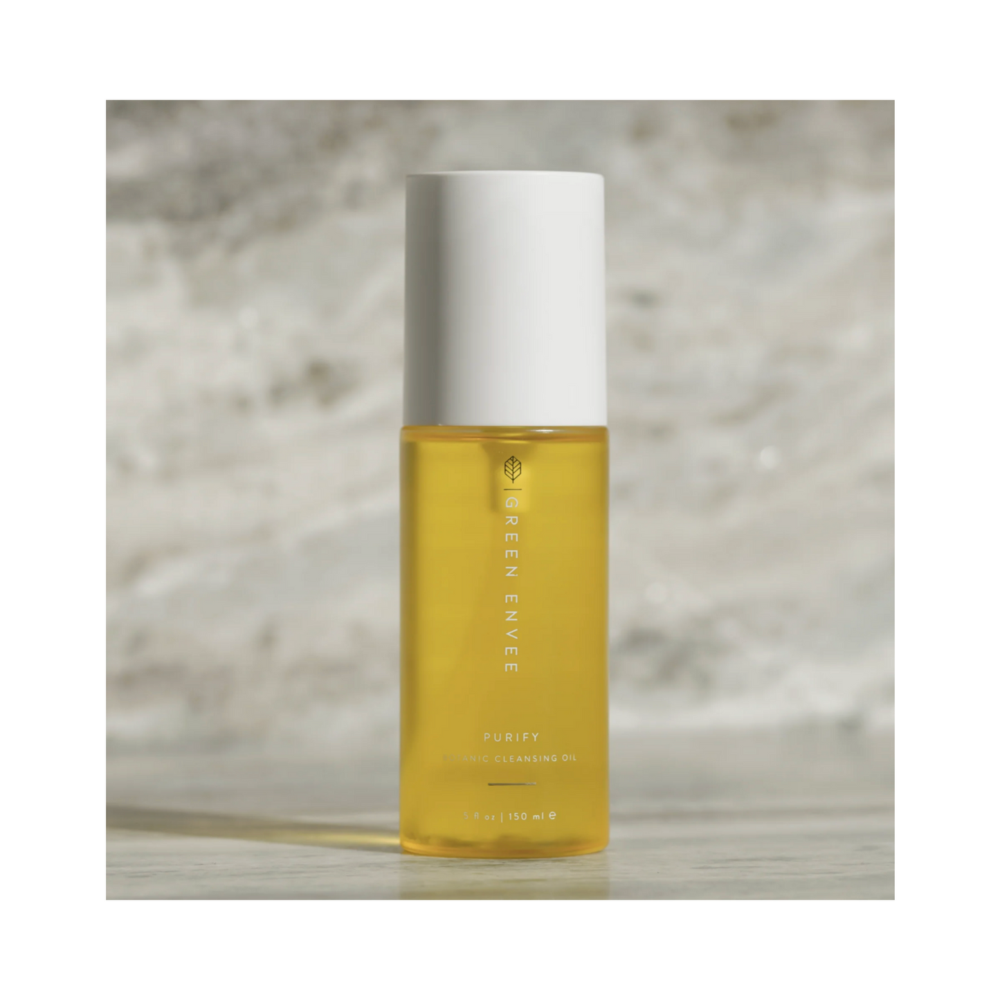 Green Envee Purify Botanic Cleansing Oil bottle on stone background. Botanical cleansing oil designed for gentle face and neck cleansing.