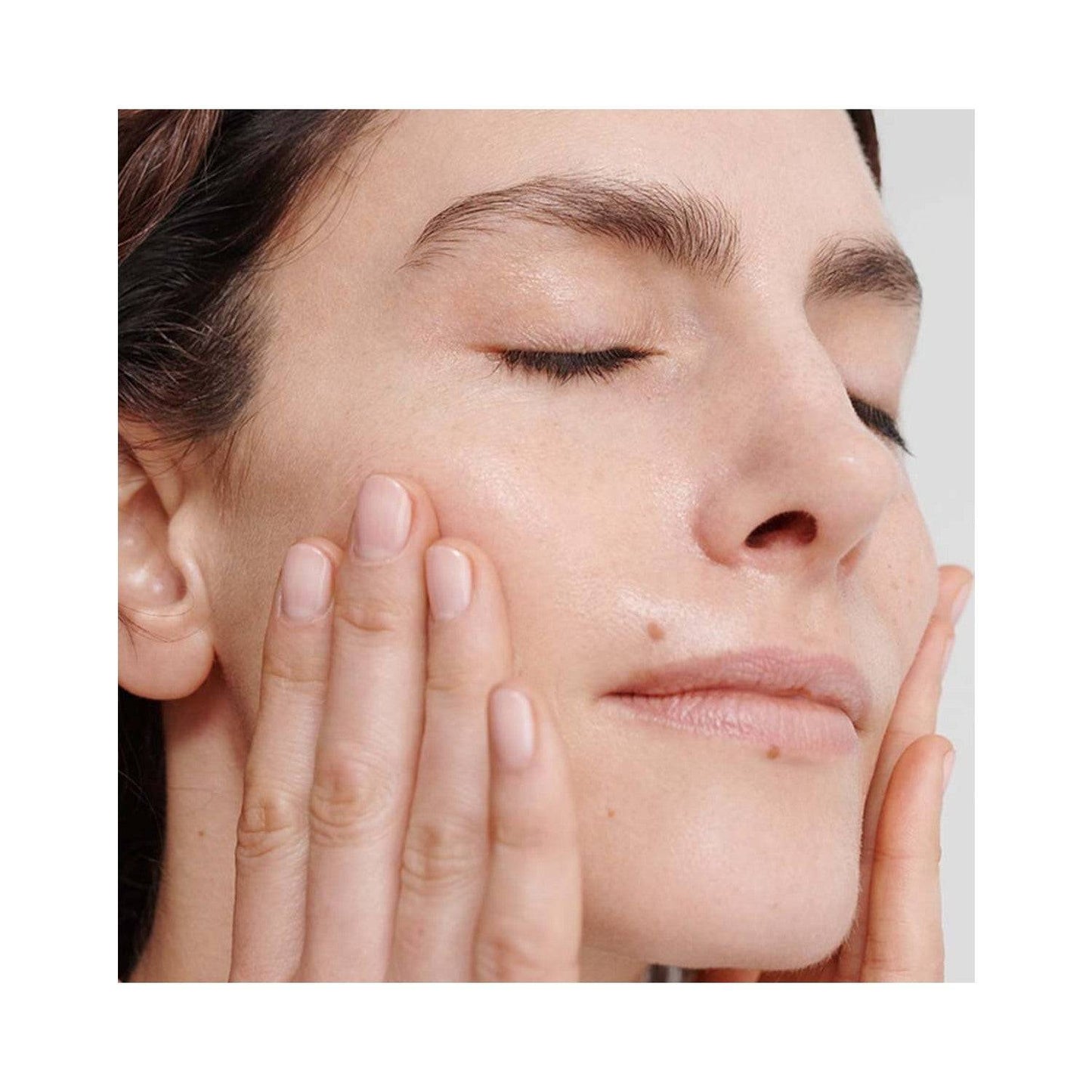 Close-up of woman massaging Dr Hauschka Regenerating Intensive Treatment into her skin, promoting hydration and renewal.
