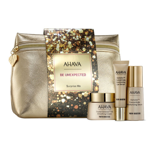 Close-up of gold cosmetic bag with glittery gift tag, showcasing Ahava skin care promotional kit with eye serum, moisturizer, and cream