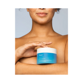 Murad Moisturizing Body Pads in blue jar held by woman, part of acne control skincare for smooth and clear skin.