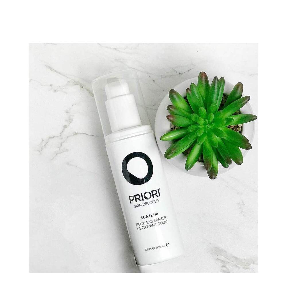 Priori AHA Gentle Facial Cleanser placed on marble surface beside green succulent, highlighting clean beauty and skincare aesthetic.