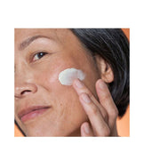Woman applying Dr Dennis Gross Advanced Retinol Wrinkle Cream to face. Hydrating cream reduces wrinkles and improves skin tone.