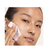 Close-up of woman using Alpha Beta Daily Peel pad by Dr Dennis Gross, targeting uneven texture and dullness for a youthful glow.