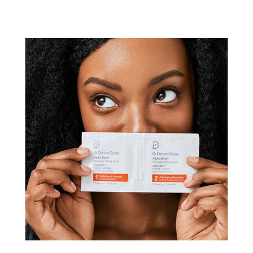 Model holding Dr Dennis Gross Alpha Beta Daily Peel sachets, highlighting 2-step anti-aging and exfoliating skincare system for daily application.