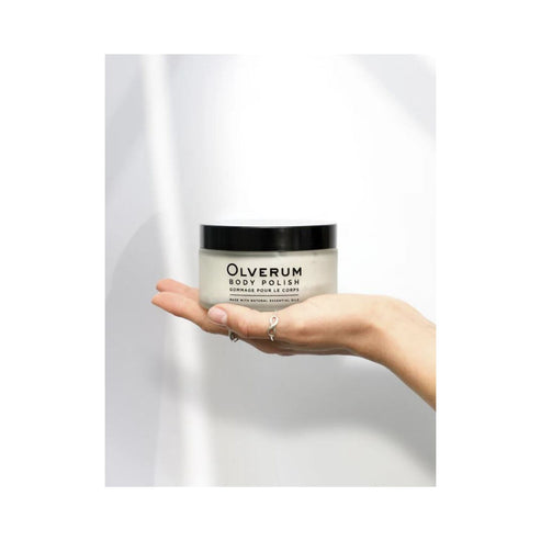 Close-up of fingers scooping Olverum Body Polish from jar. Creamy formula enriched with natural essential oils for body care.