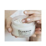 Woman applying Olverum Body Polish to shoulder area. Exfoliating body treatment for soft, nourished skin using natural ingredients.