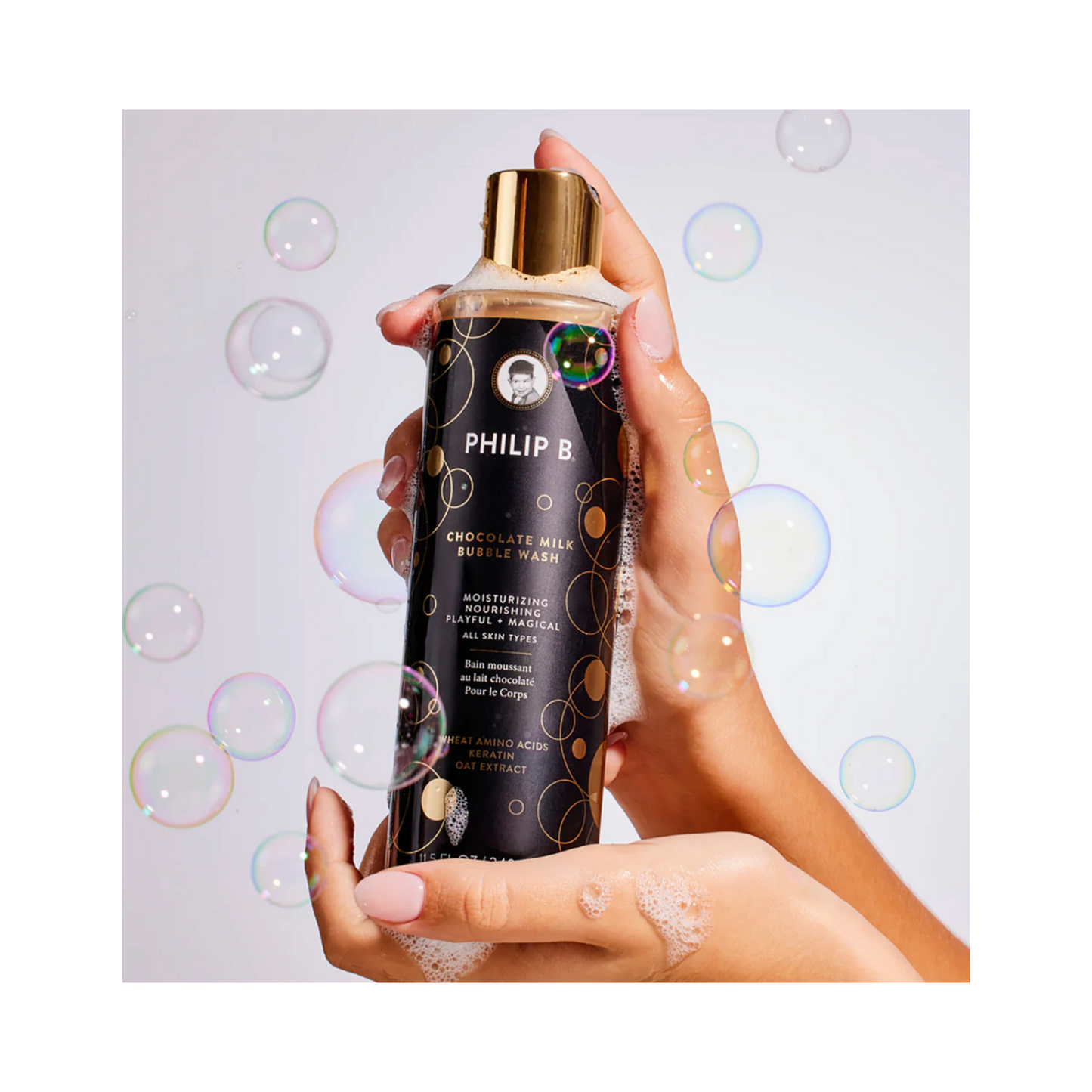 Foamy Philip B Botanical Chocolate Milk Bubble Wash held in hands, surrounded by bubbles, perfect for a luxurious shower experience.