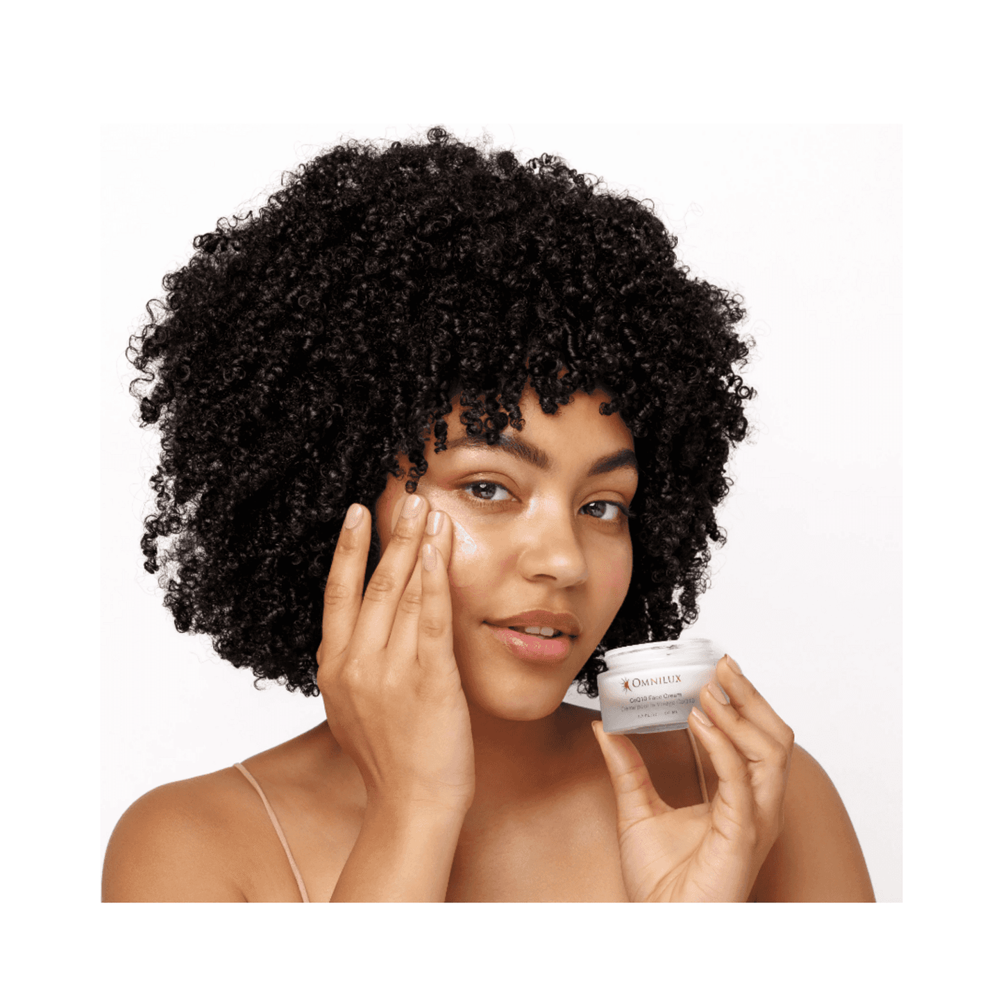 Model applying Omnilux CoQ10 Face Cream to face, showcasing its use for hydration and post-LED skincare treatment.
