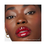Model applying Jane Iredale Colorluxe Lip Glaze in Flush, featuring a soft pink gloss that enhances natural lip color with shine.