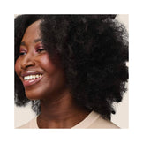 Smiling woman with defined, voluminous curls after using Living Proof Curl Elongator, showcasing frizz-free, shiny hair results.