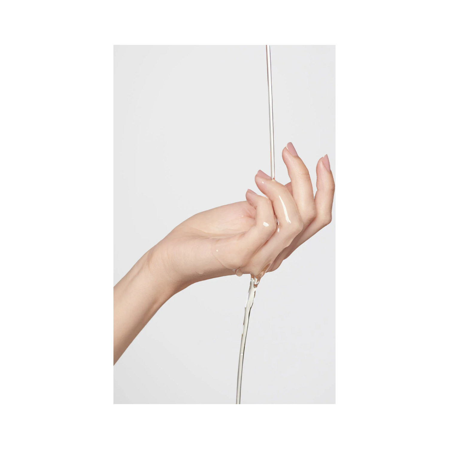 Clear cleansing oil from 111SKIN flowing onto a hand, emphasizing its lightweight and nourishing texture.