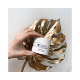 Hand holding Janssen Detox Face Cream jar over a decorative gold leaf, showcasing luxury skincare for detoxifying and moisturizing.