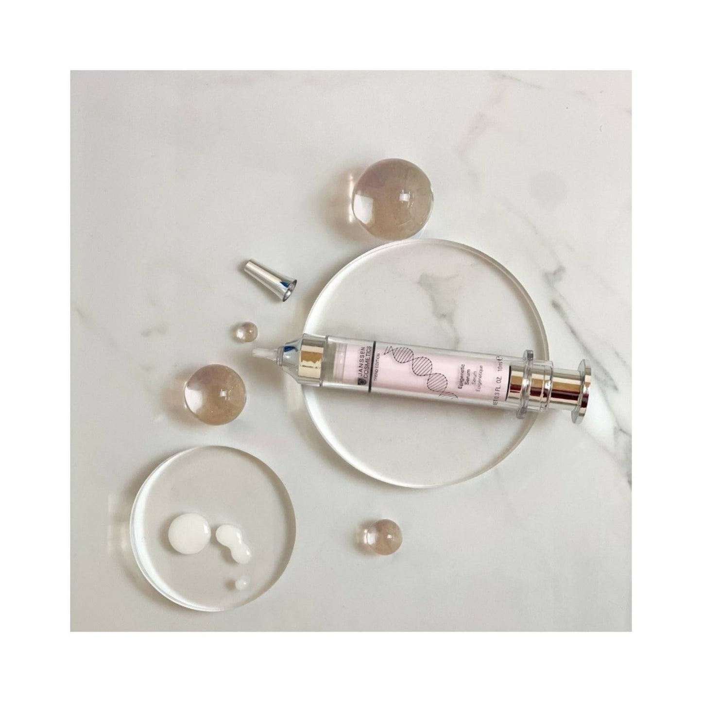 Flat lay of Janssen Epigenetic Serum with serum drops and clear spheres. Innovative face serum to preserve skin vitality and firmness.