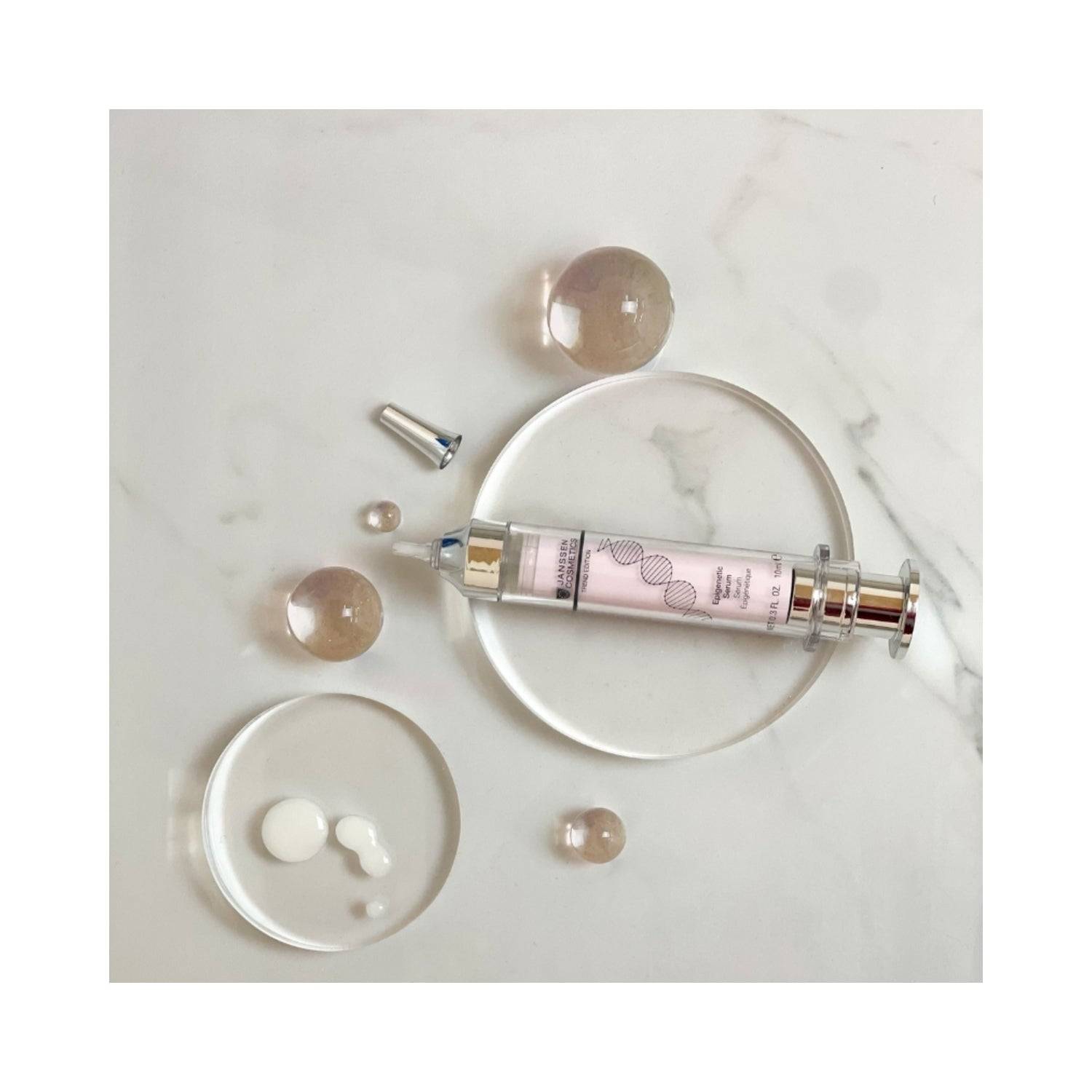 Flat lay of Janssen Epigenetic Serum with serum drops and clear spheres. Innovative face serum to preserve skin vitality and firmness.
