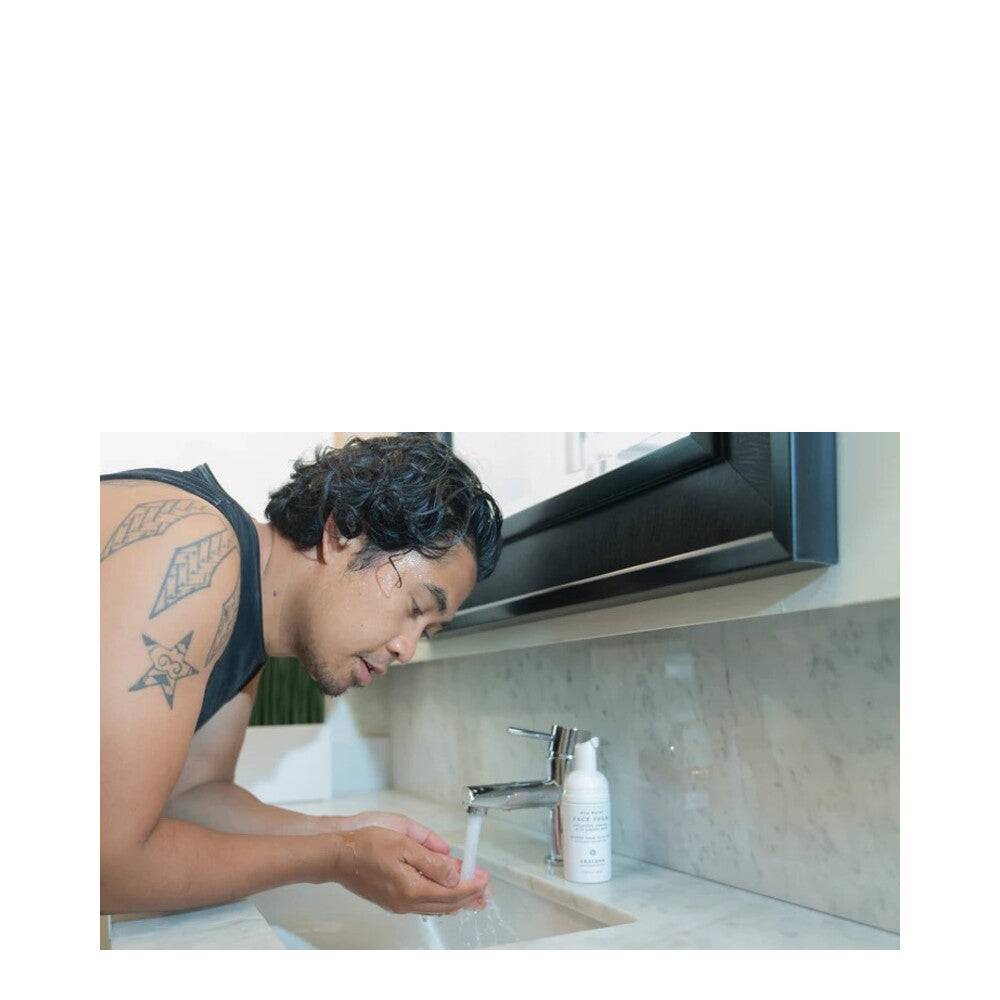 Man rinsing off Graydon Face Foam Cleanser at a bathroom sink, highlighting daily use of natural BHA and azelaic acid formula for clear skin.