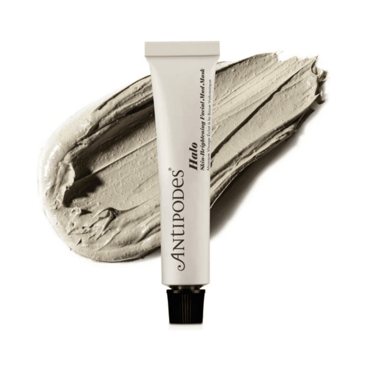 Antipodes Halo Skin-Brightening Facial Mud Mask tube displayed over a textured smear of the mud mask, highlighting its creamy formula.