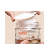 Avene Hyaluron Activ B3 Cream refill being inserted into glass jar, promoting sustainable skincare with firming and hydrating benefits.