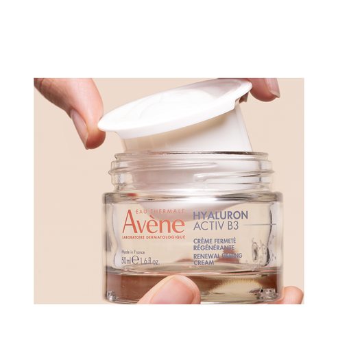 Avene Hyaluron Activ B3 Cream refill being inserted into glass jar, promoting sustainable skincare with firming and hydrating benefits.