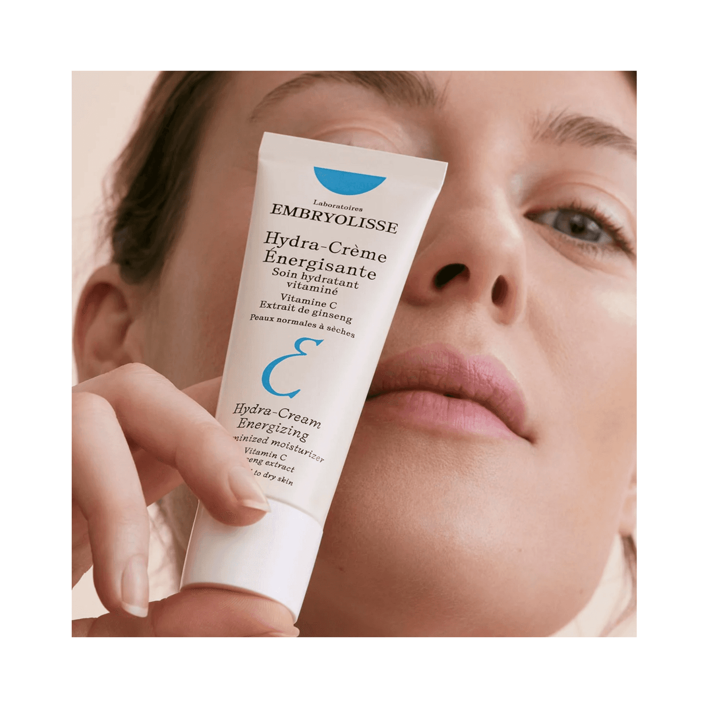 Woman holding Embryolisse Hydra Cream Energizing close to her face, showcasing its use for boosting hydration and revitalizing dry skin.