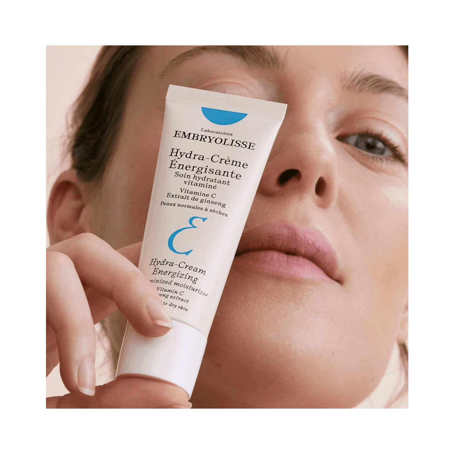 Woman holding Embryolisse Hydra Cream Energizing close to her face, showcasing its use for boosting hydration and revitalizing dry skin.