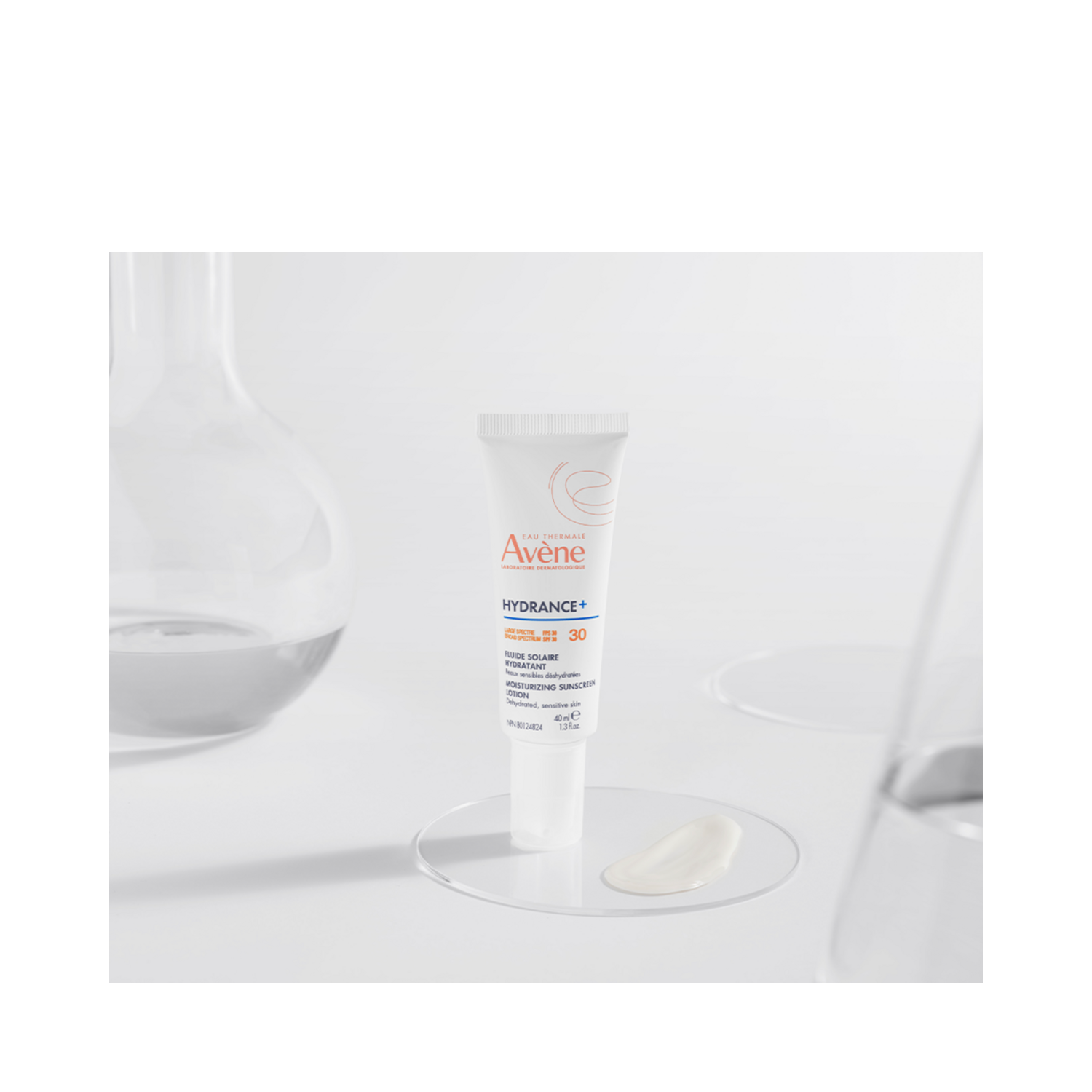 Avene Hydrance Sunscreen SPF 30 tube displayed on a glass surface with lotion swatch, highlighting its lightweight, hydrating formula.