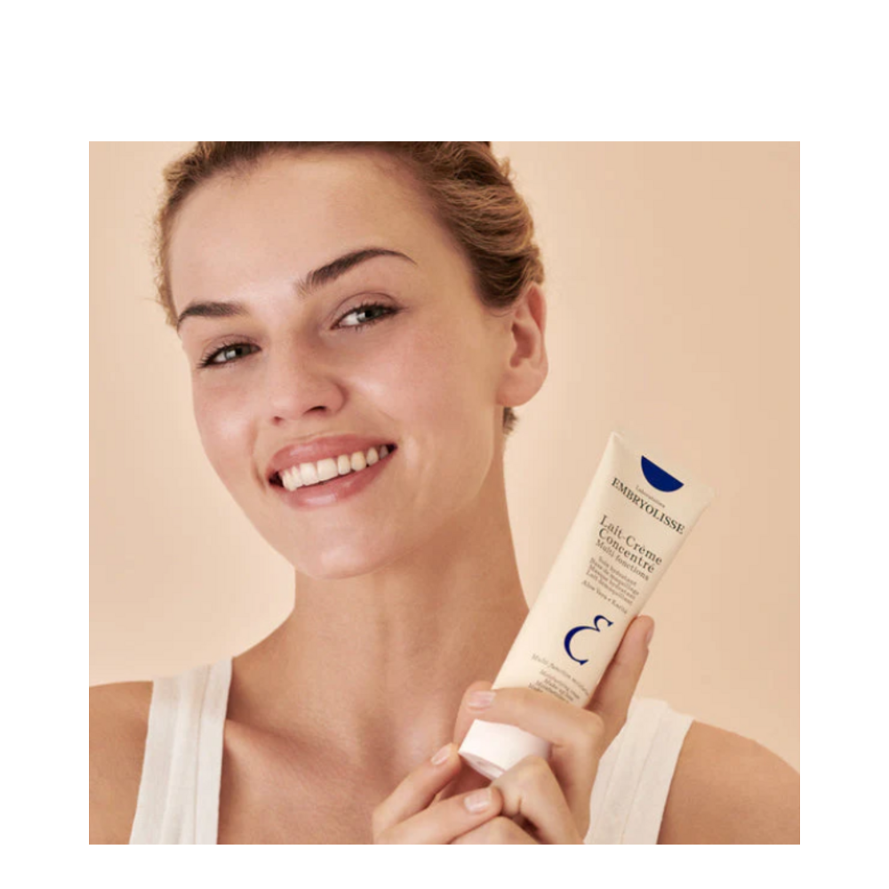 Smiling woman holding Embryolisse Cream, showcasing its popularity and effectiveness as a dermatologist-favorite face moisturizer.