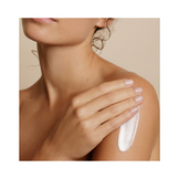 Embryolisse Lait Creme Fluid+ bottle resting between two bare shoulders, emphasizing its multi-use skincare benefits for all skin types.