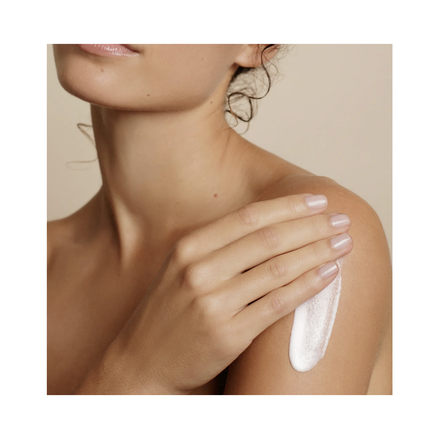 Embryolisse Lait Creme Fluid+ bottle resting between two bare shoulders, emphasizing its multi-use skincare benefits for all skin types.