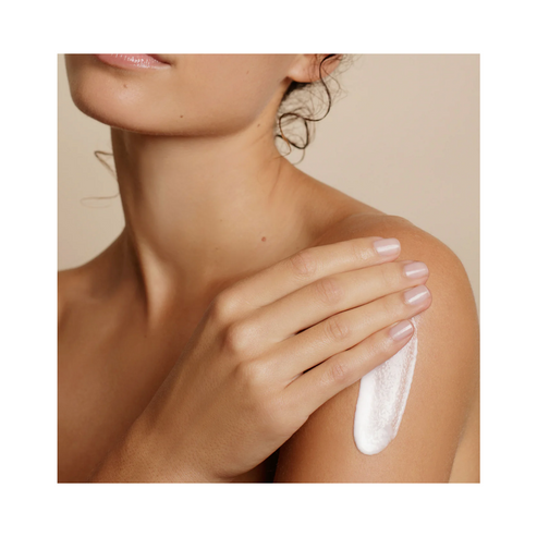 Embryolisse Lait Creme Fluid+ bottle resting between two bare shoulders, emphasizing its multi-use skincare benefits for all skin types.