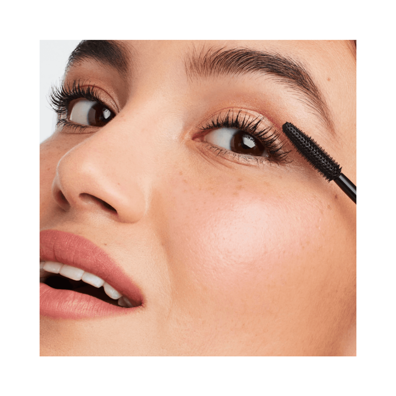 Woman applying Jane Iredale Lash Fixation Tubing Mascara, emphasizing lash length and definition with smudge-resistant formula.