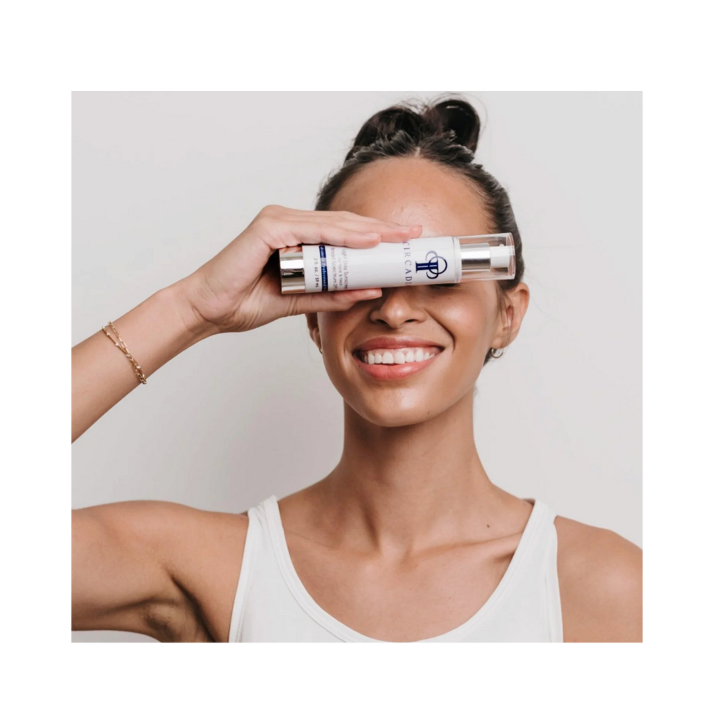 Smiling woman holding Circadia Light Day Sunscreen Broad Spectrum SPF-37, highlighting skincare for daily sun protection and hydration.