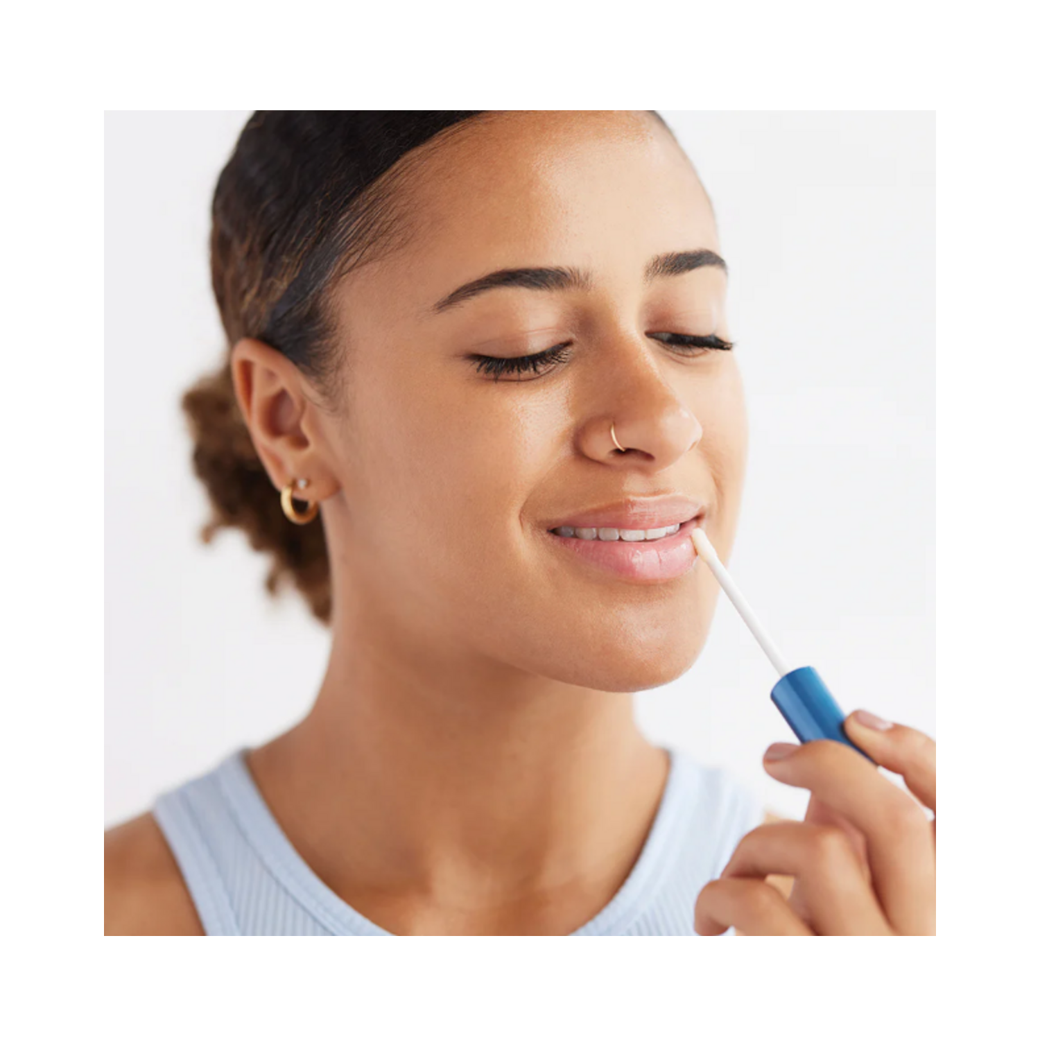 Woman applying Bioelements Lip Clinic Hydrating Serum with applicator, demonstrating its use for smooth, nourished lips in daily skincare routine.