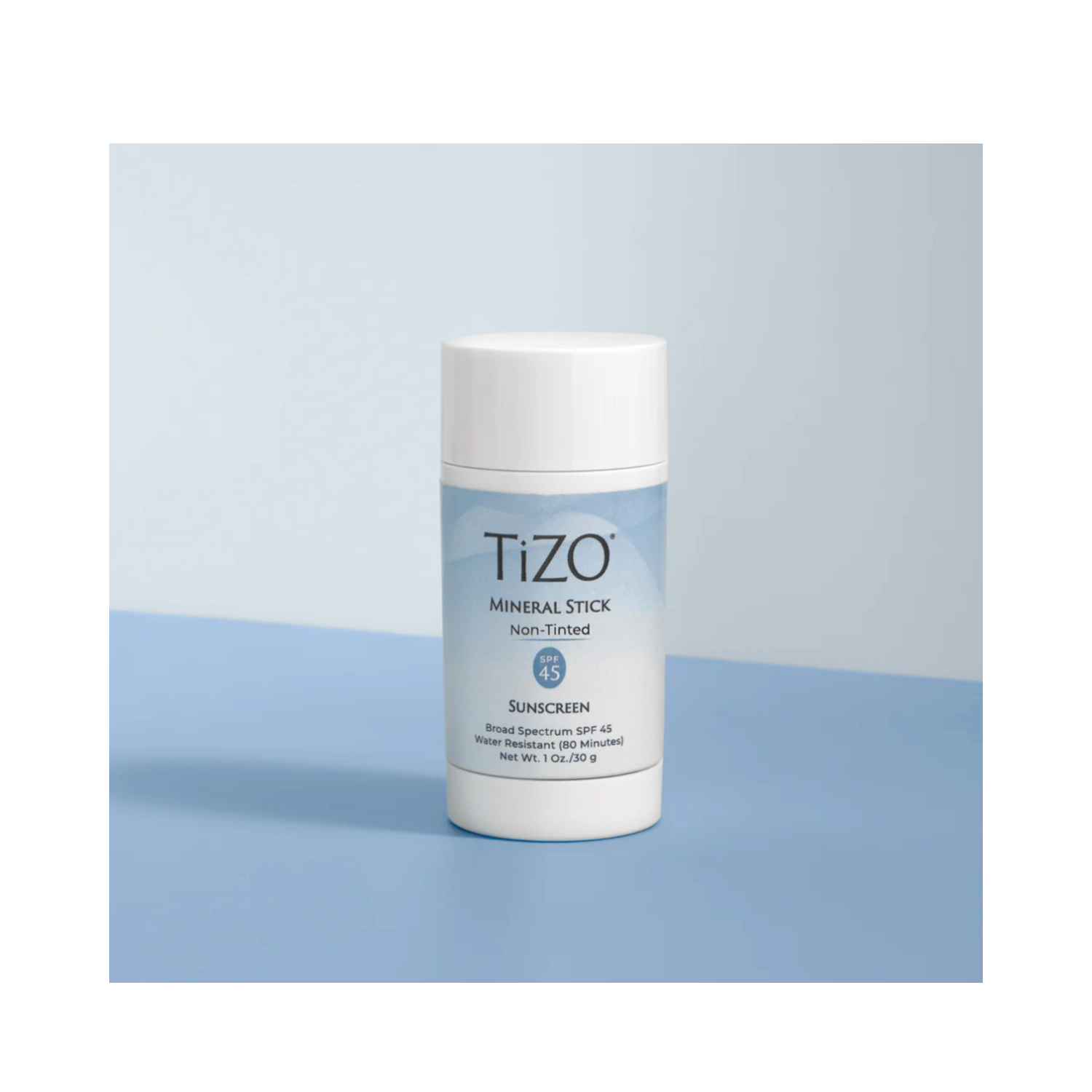 TiZO Mineral Stick Non Tinted Sunscreen SPF 45 standing upright on a blue background, highlighting its sleek, travel-friendly packaging.