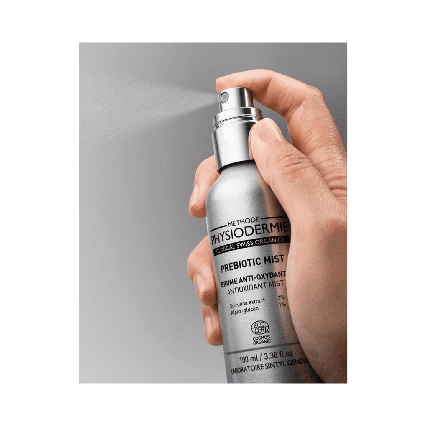 Hand spraying Physiodermie Prebiotic Mist Antioxydant Face Mist, showcasing fine mist application for antioxidant skin care benefits.