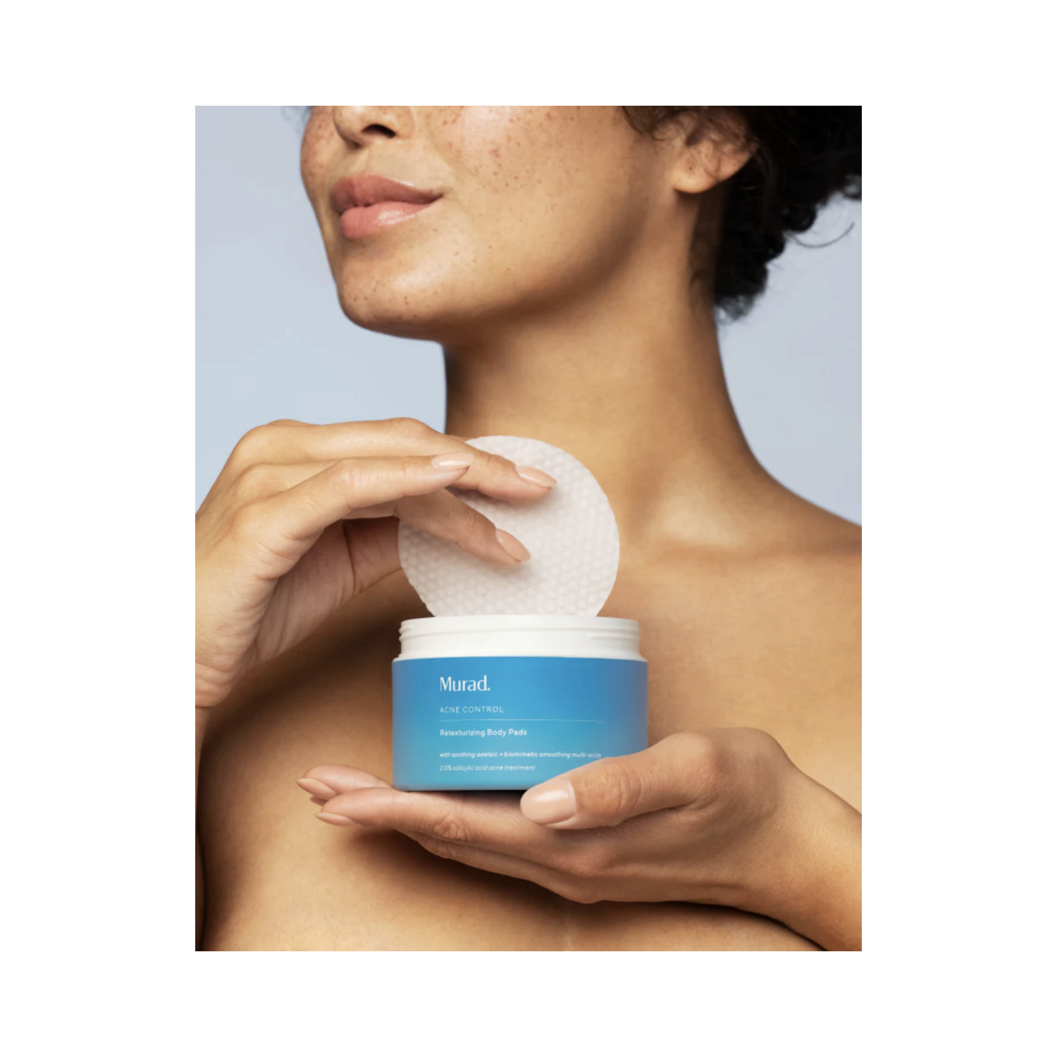 Close-up of woman applying Murad Retexturizing Body Pads. Exfoliating pads help calm irritated skin and smooth rough texture on body.