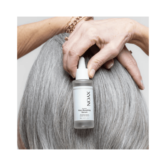 Kvinna som applicerar XYON Revitalize Hair-Boosting Serum i grått hår, främjar näring av hårbotten och höjer hårvolymen.