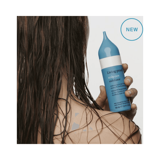Woman holding Living Proof Scalp Care Exfoliator with wet hair, showcasing its use as a pre-shampoo treatment to reduce scalp buildup and oil.