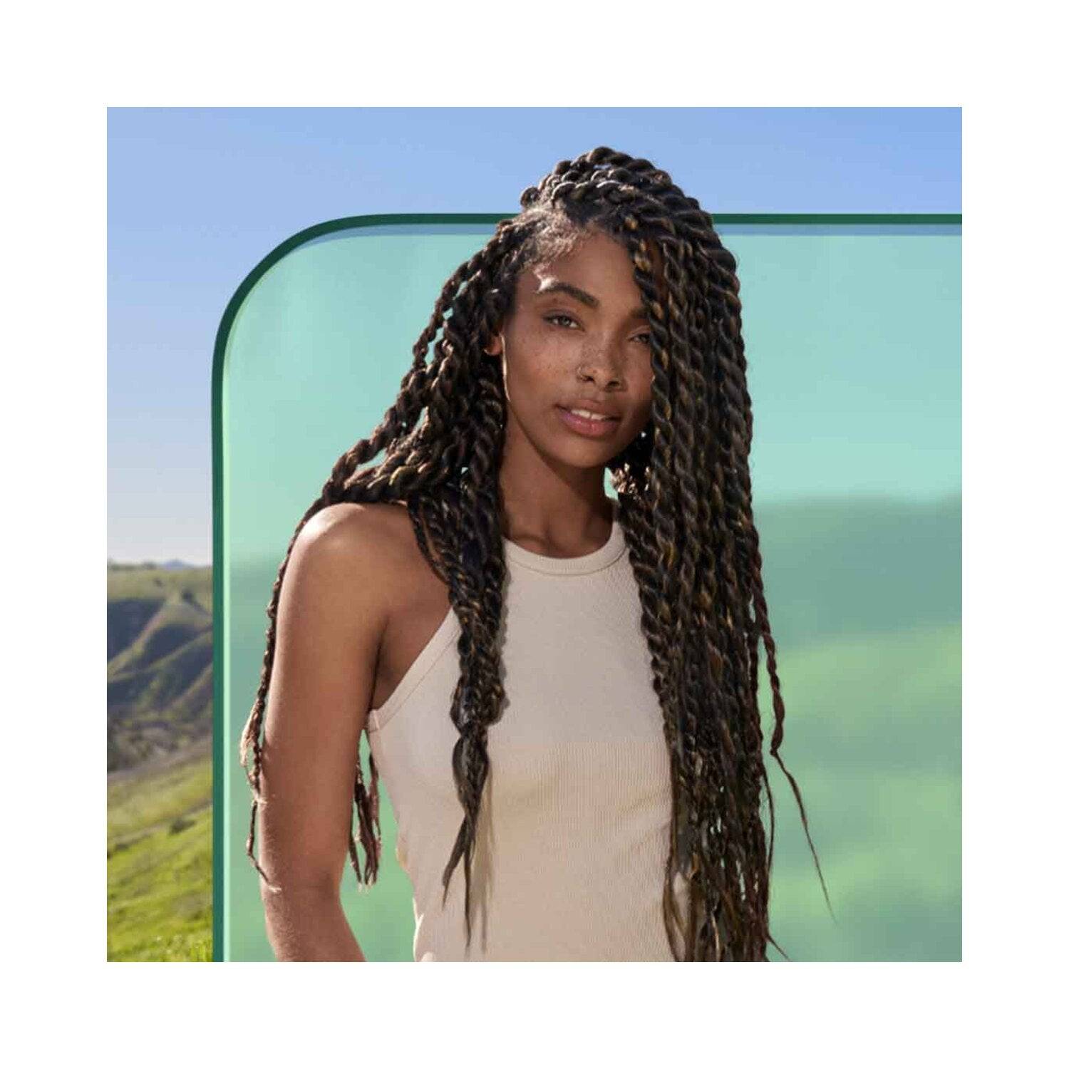 Model with long, healthy braids showcasing results of Biolage Scalp Sync Shampoo, promoting scalp hydration and hair care for all hair types.