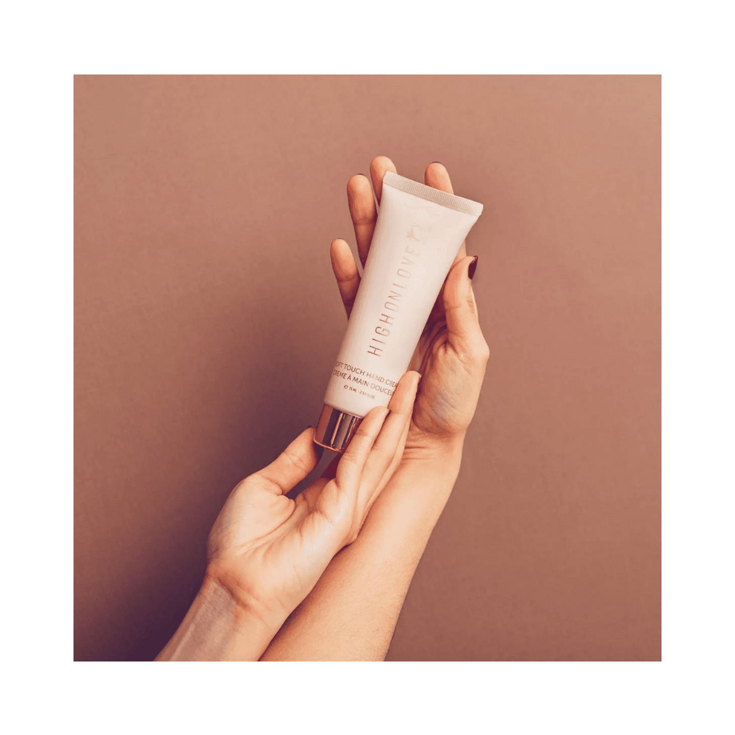 Hands holding High on Love Soft Touch Hand Cream, showcasing its elegant packaging for hand and foot hydration from eSkinStore.