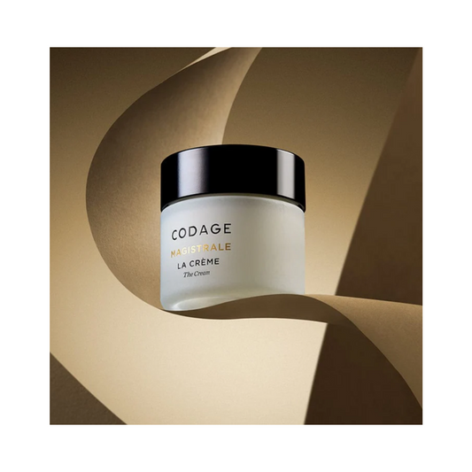 Codage Paris La Crème Visage Magistrale Crème présentée sur un fond abstrait doré, soulignant son attrait de soin haut de gamme.