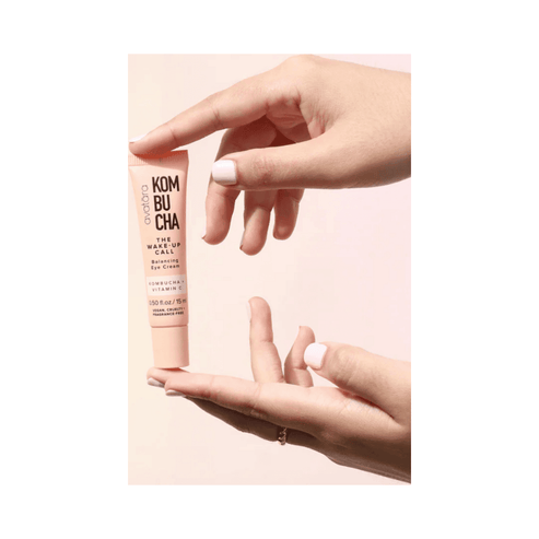 Hands holding Avatara The Wake-Up Call Eye Cream, a brightening under-eye treatment with Vitamin C and Kombucha for puffiness and hydration.