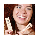 Smiling woman holding Avatara The Wake-Up Call Eye Cream and box, showcasing brightening and puffiness-reducing benefits for under-eye care.