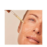 Woman applying Dr Dennis Gross Vitamin C Firming Serum to face, demonstrating skincare use for firming and reducing fine lines.